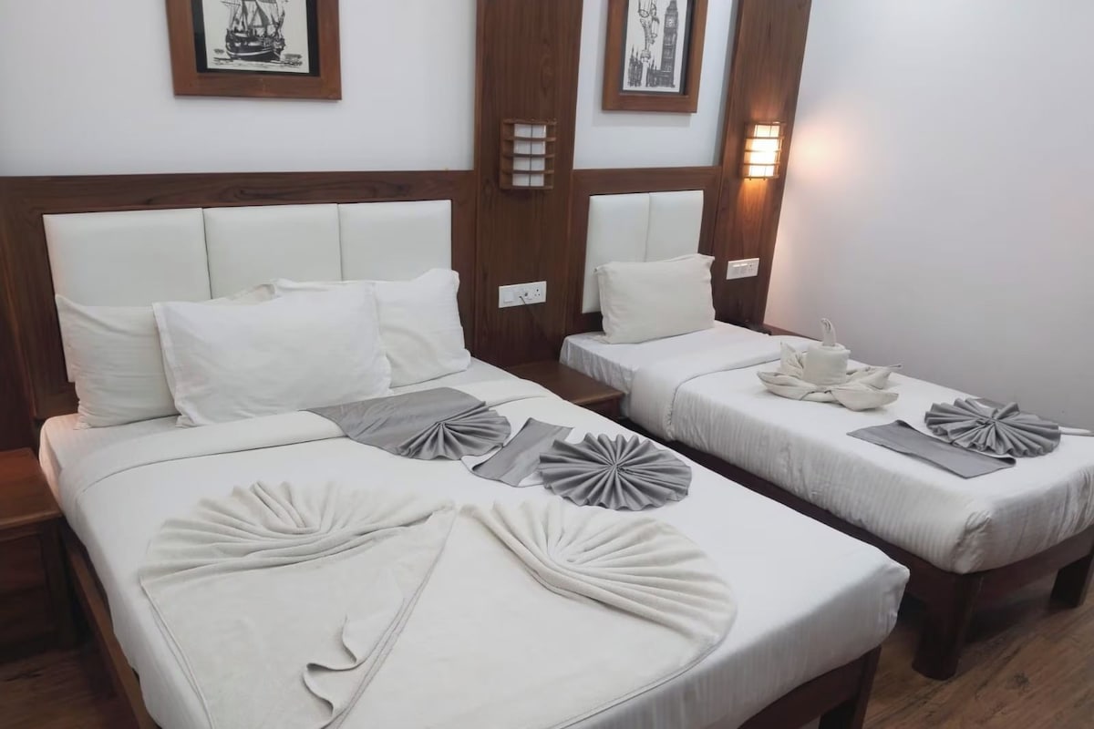 Habitación de hotel con dos camas, cada una con ropa blanca y almohadas decorativas.