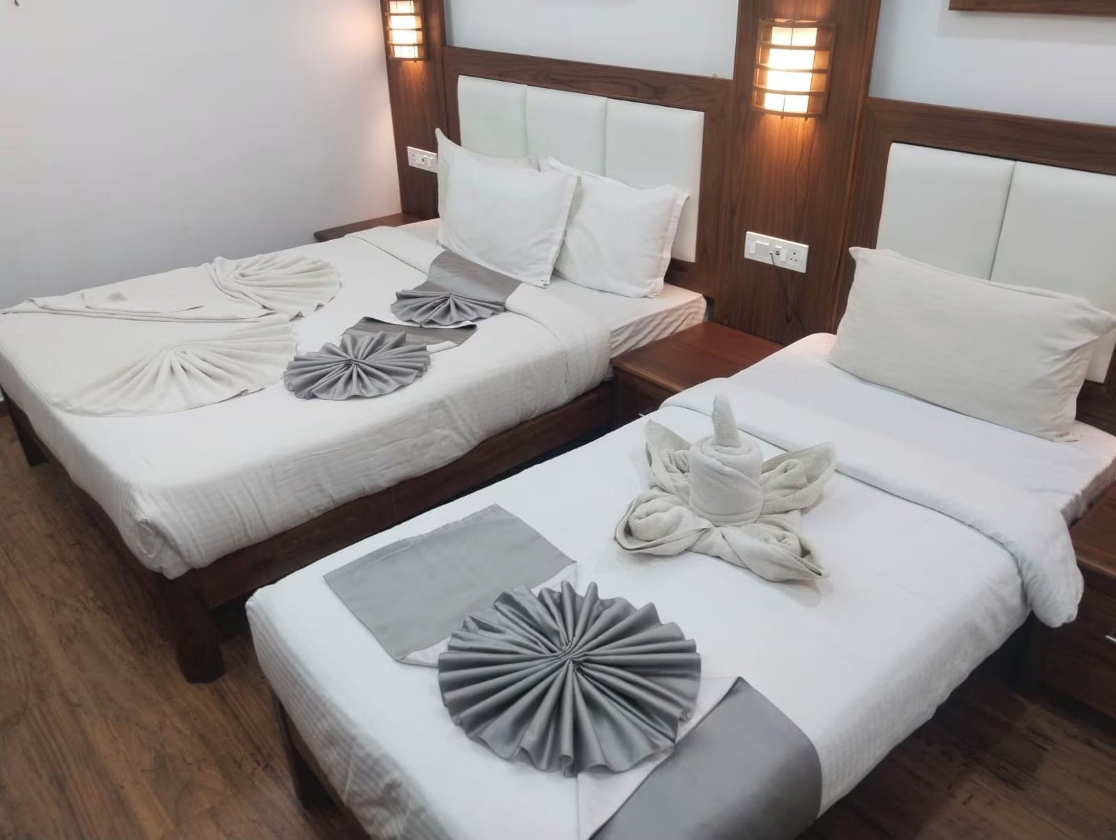 Two twin beds with headboards, each with a pillow and a towel arranged on the bed.