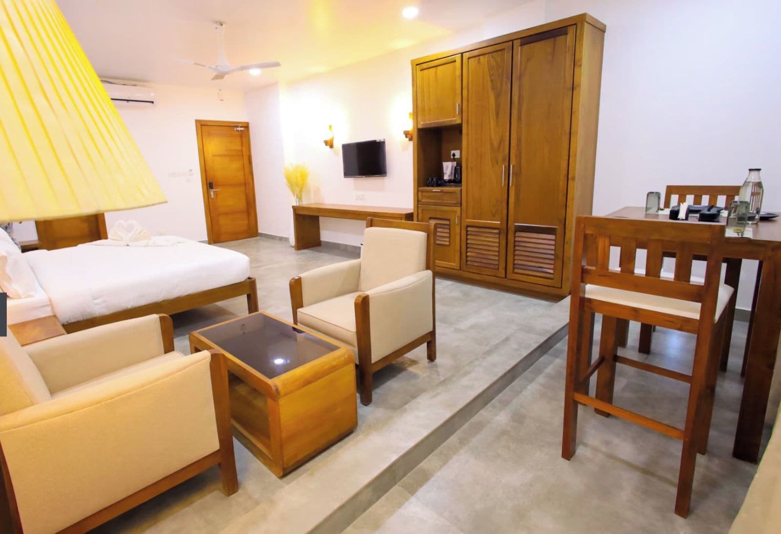 Habitación de hotel con cama, dos sillones, una mesita de centro, un escritorio, un televisor y un armario.