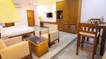 Habitación de hotel con cama, dos sillones, una mesita de centro, un escritorio, un televisor y un armario.