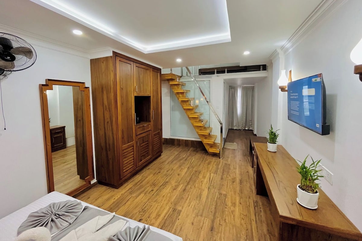 Un interior moderno con una escalera de madera, un armario grande y un televisor de pantalla plana montado en la pared.