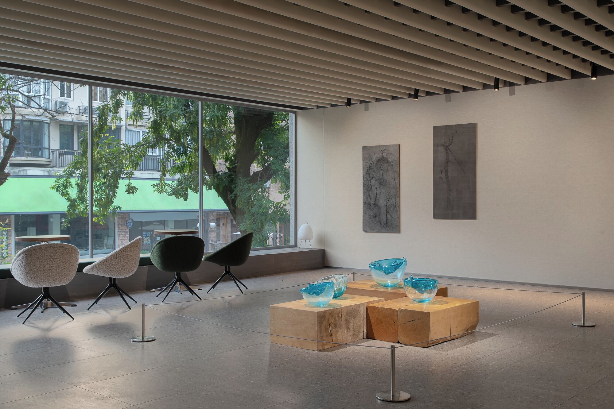 An art gallery with modern chairs, abstract paintings, and glass sculptures on display.