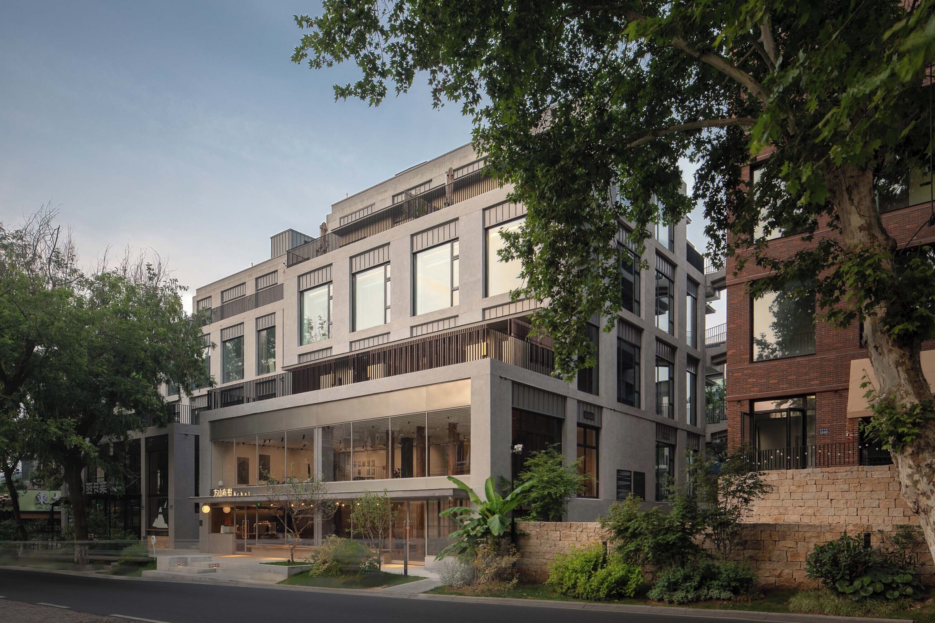 A modern multi-story hotel with large windows, a glass facade, and a landscaped front yard.