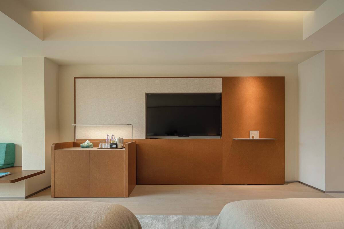 Una habitación de hotel moderna con un mostrador de recepción de madera, un televisor de pantalla plana y un estante pequeño.