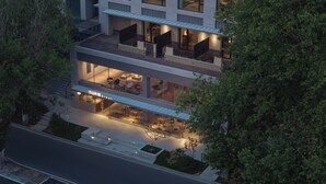 A multi-story hotel with a glass facade, outdoor seating area, and a visible restaurant. - Árbol Moganshan Yucun (Huzhou)