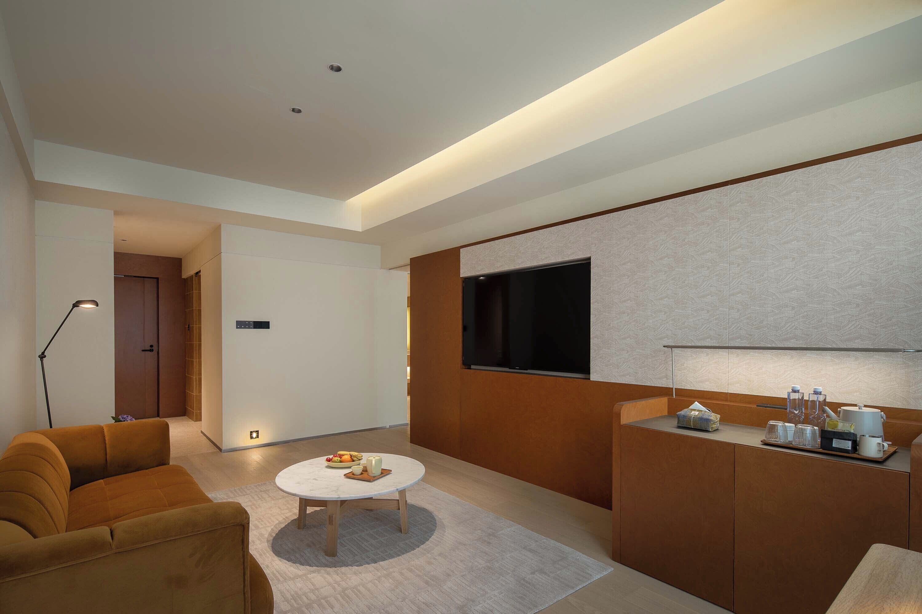 A modern living room with a sofa, coffee table, and a TV mounted on the wall.