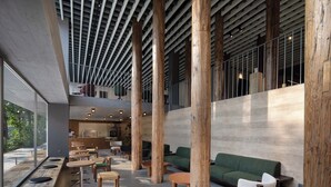 A modern interior with wooden pillars, seating areas, and a kitchen visible in the background. - Árbol Moganshan Yucun (Huzhou)