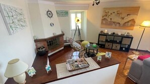 Una sala de estar con chimenea, una mesa de centro con revistas, una lámpara y un sofá.