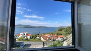 Vista desde una ventana hacia un lago con casas y cielo despejado.