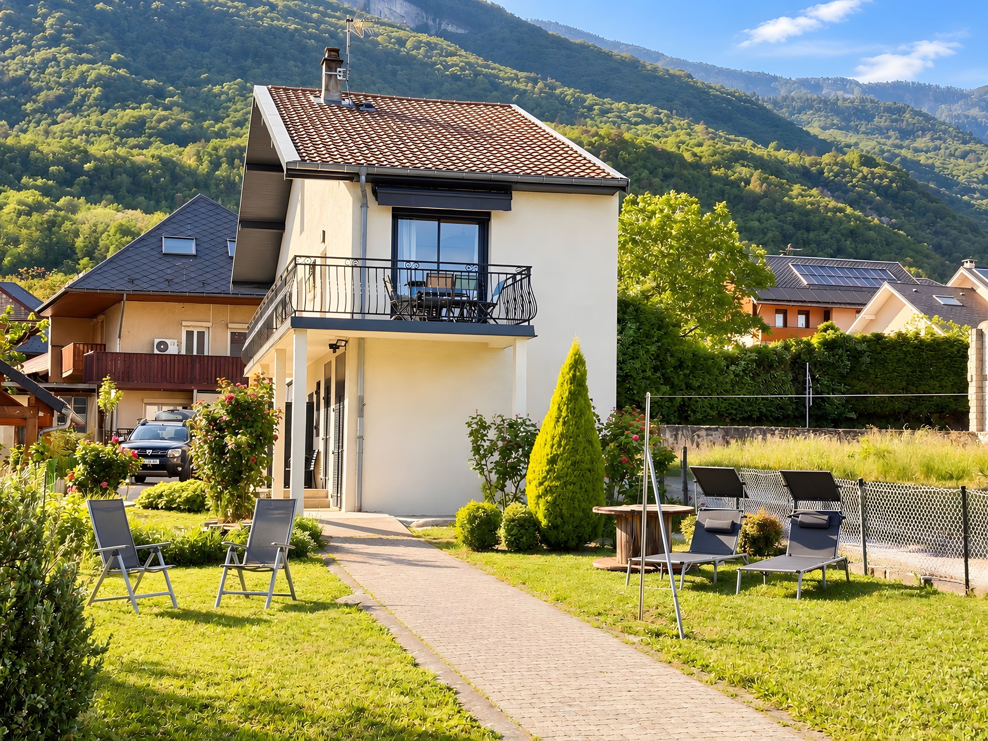 Ein zweistöckiges Haus mit einem Balkon, einem gepflasterten Weg und einem Rasen.