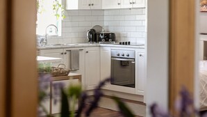 A modern kitchen with white cabinets, a built-in oven, and a coffee maker. - The Art Lovers Cottage in Mandurah 2BR (Dudley Park)