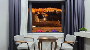 A room with two chairs, a table, and a view of a lit-up building at night. - Hasan Pasa Konagi (Mardin)