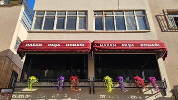Un edificio con dos escaparates, cada uno con un toldo rojo y el nombre "HASAN PAŞA KONAGI".