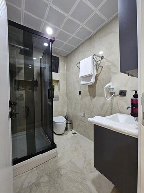 Deluxe driepersoonskamer, terras | Badkamer | Een douche, een haardroger, handdoeken, zeep