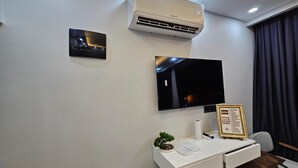 A modern room with a white desk, a mounted TV, an air conditioner, and a small potted plant. - Hasan Pasa Konagi (Mardin)