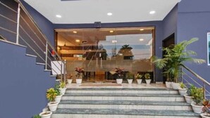 A hotel entrance with a glass door, marble steps, and potted plants. - Hotel Grand Bella (Jaipur)