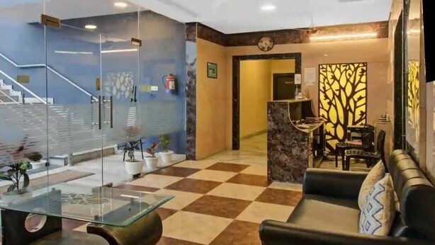 A lobby with a checkered floor, a reception desk, a staircase, and seating areas. - Hotel Grand Bella (Jaipur)