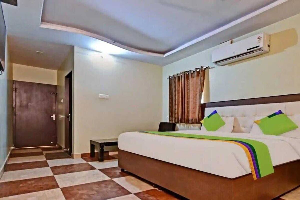 Ein Hotelzimmer mit Bett, Klimaanlage, kleinem Tisch und einem karierten Boden.