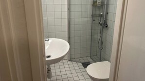 A small bathroom with a sink, toilet, and glass-enclosed shower. - Charming Two Rooms Apartment in Stockholm (Stockholm)