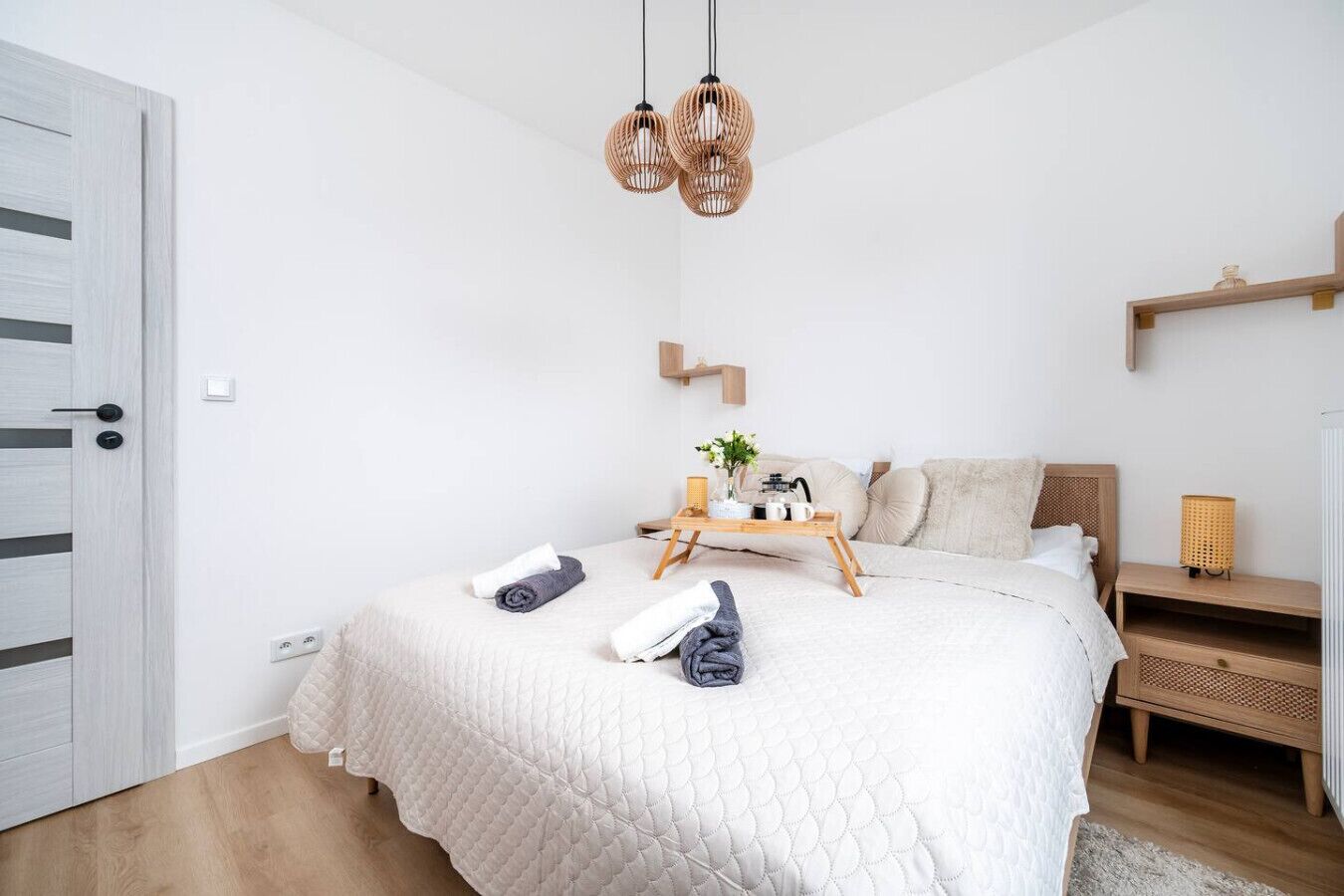 Una camera da letto moderna con un letto grande, comodini, una lampada da comodino e un lampadario.