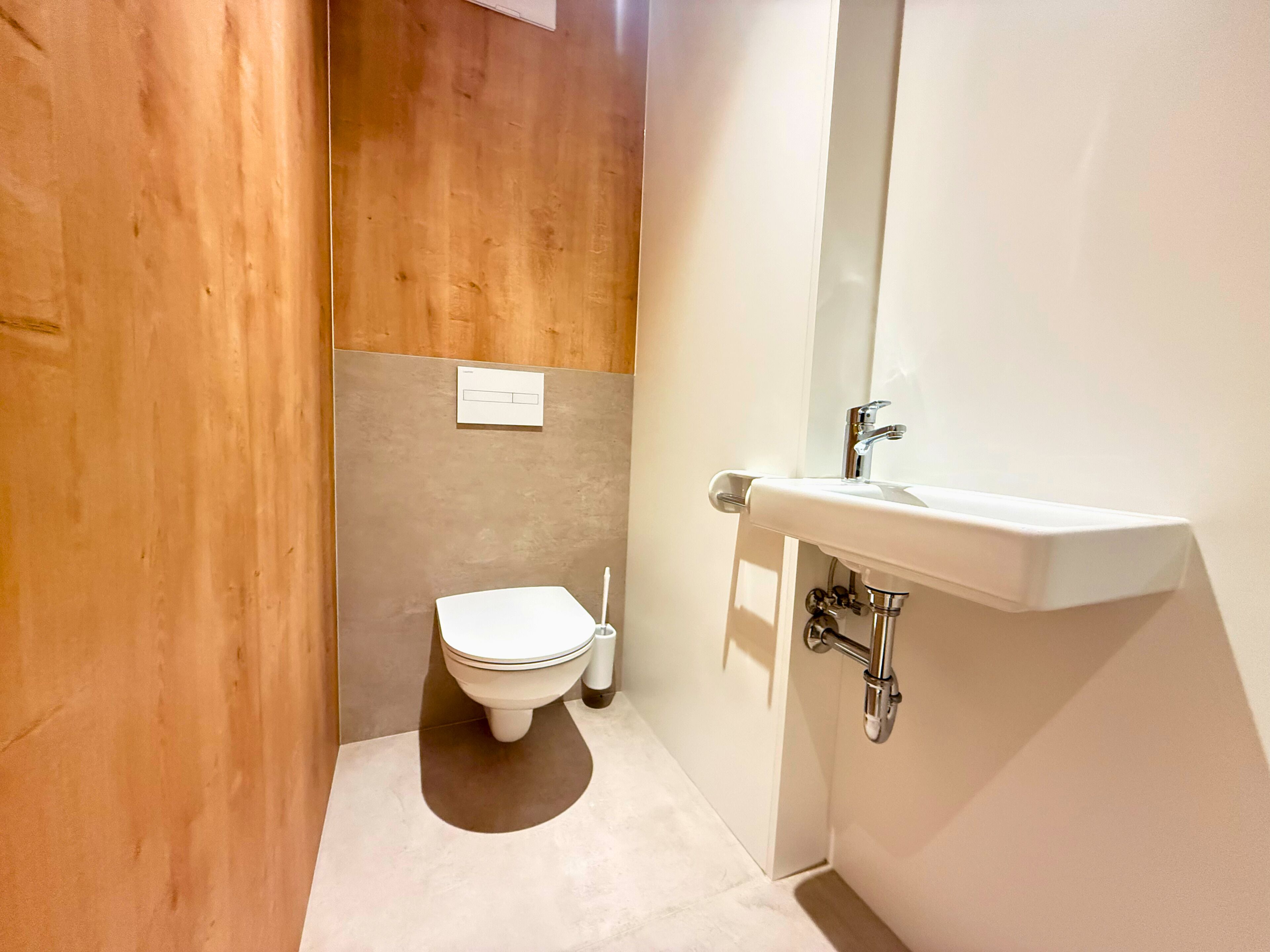 A modern bathroom with a toilet, sink, and mirror.
