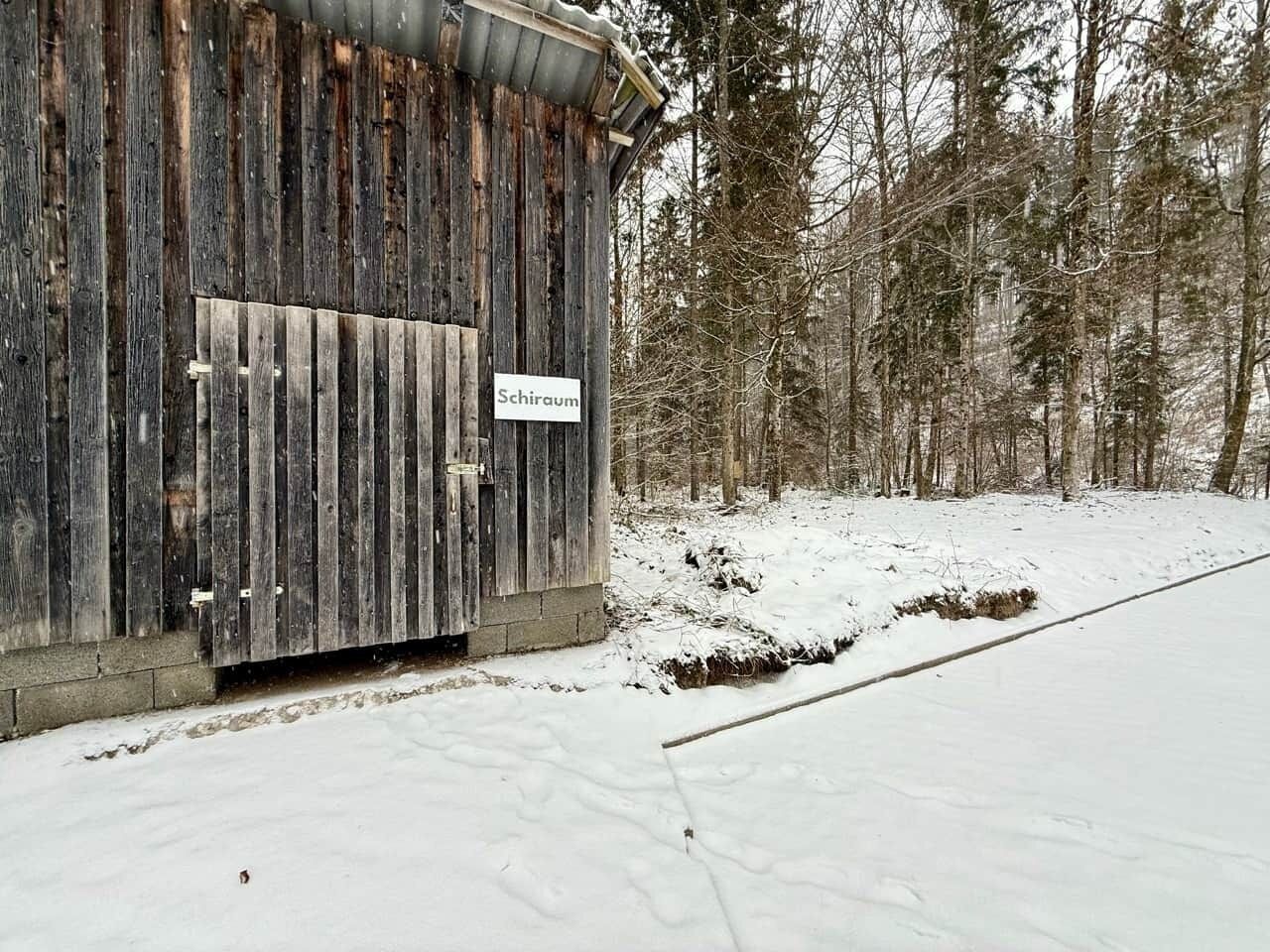 Een rustiek houten gebouw met een bord waarop ‘Schirau’ staat.