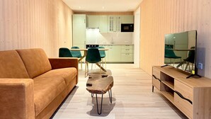 A modern living room with a sofa, a coffee table, and a TV on a wooden stand. - | 1 bedroom | Shower | (Grünau im Almtal)