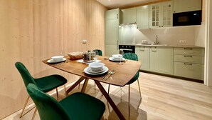 A modern kitchen with wooden cabinets, a dining table with chairs, and a microwave above the counter. - | 1 bedroom | Shower | (Grünau im Almtal)