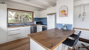 A modern kitchen with white cabinets, a wooden countertop, and a blue backsplash. - Walk to Beach | Pet Friendly | Sleep 5 (Ocean Grove)