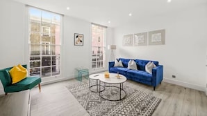 A modern living room with a blue sofa, a green armchair, and a patterned rug. - Chic Beauchamp Place Home (London)