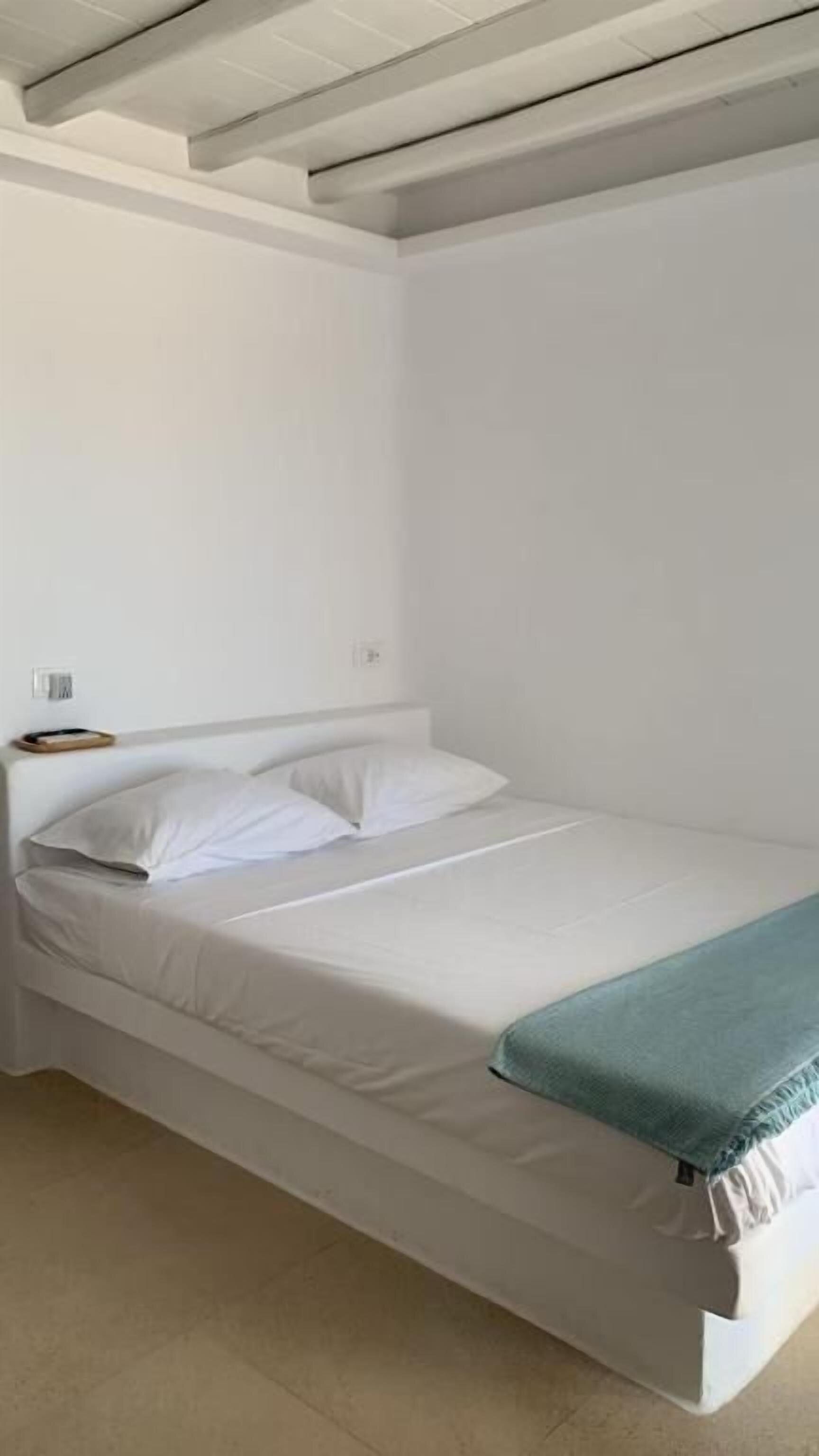 Ein Einzelbett in einem Raum mit weißen Wänden und schlichtem, klarem Design.