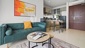 Ein modernes Wohnzimmer mit einem türkisfarbenen Sofa, einem runden Couchtisch und einem großen abstrakten Gemälde.
