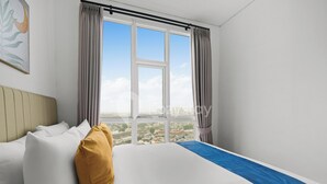 Ein Hotelzimmer mit einem großen Bett, Blick auf eine Stadtlandschaft durch ein Fenster und einem Gemälde an der Wand.