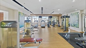 Ein modernes Fitnessstudio mit unterschiedlicher Trainingsausstattung, darunter ein PLAMAX Gerät, Laufbänder und Gewichtsbänke.