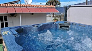 Ein Whirlpool mit blau geflecktem Äußeren, einer Tür und einer Satellitenschüssel an einem Gebäude mit rotem Dach.