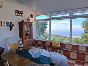 A dining area with a view of the sea, a wooden cabinet, and a bookshelf. - Bungalow Los Guanches 3 (El Paso)
