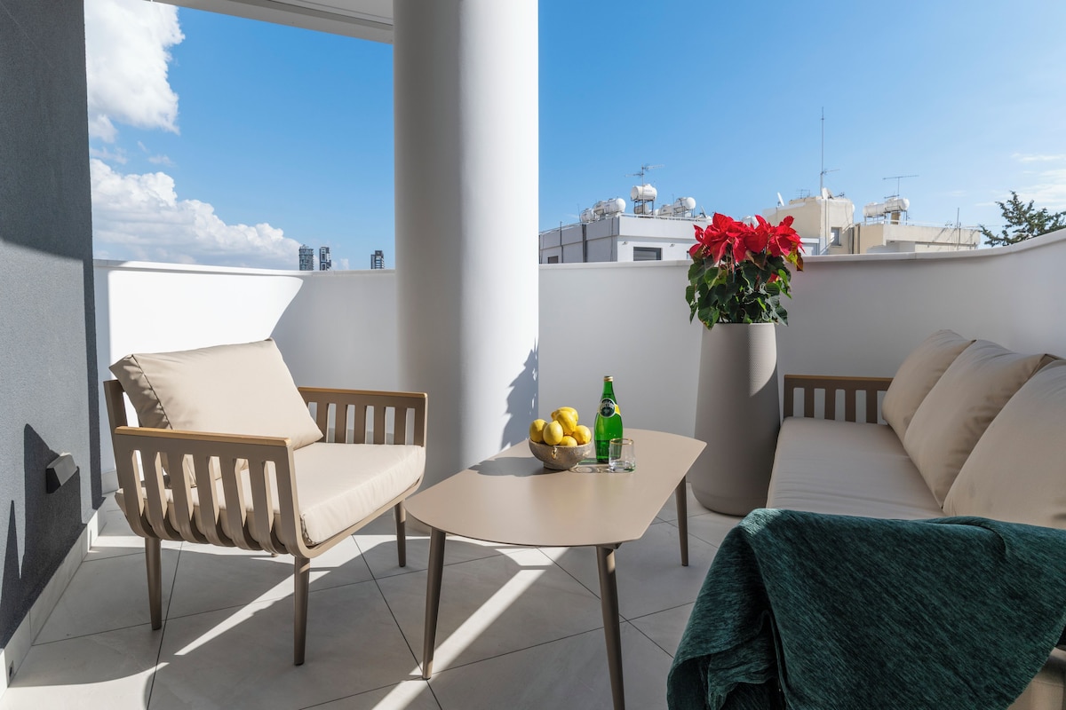 Un balcon avec un canapé, une chaise, une table et une plante en pot.