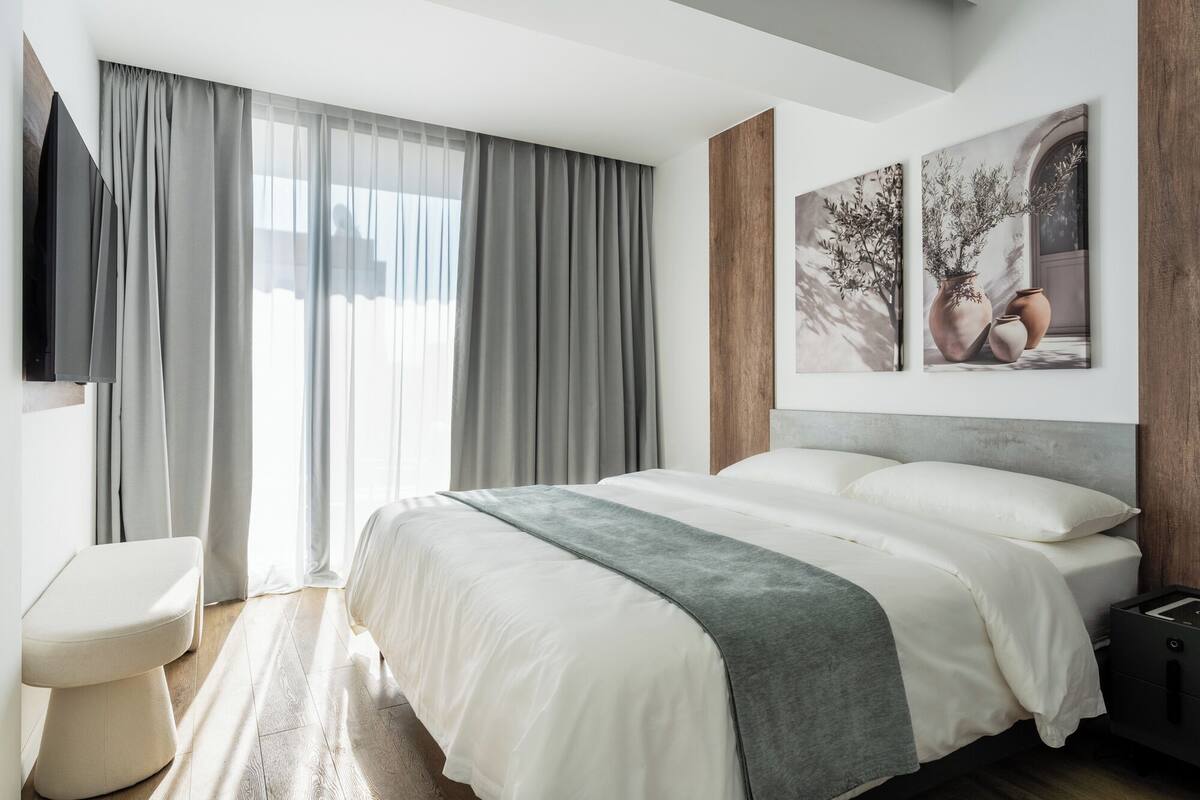 Una camera da letto moderna con un letto grande, un comodino e una TV a parete.