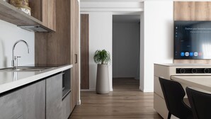 Eine moderne Küche mit Einbauofen, einer großen Küstert Pflanze und einem flachbildfernseher an der Wand.