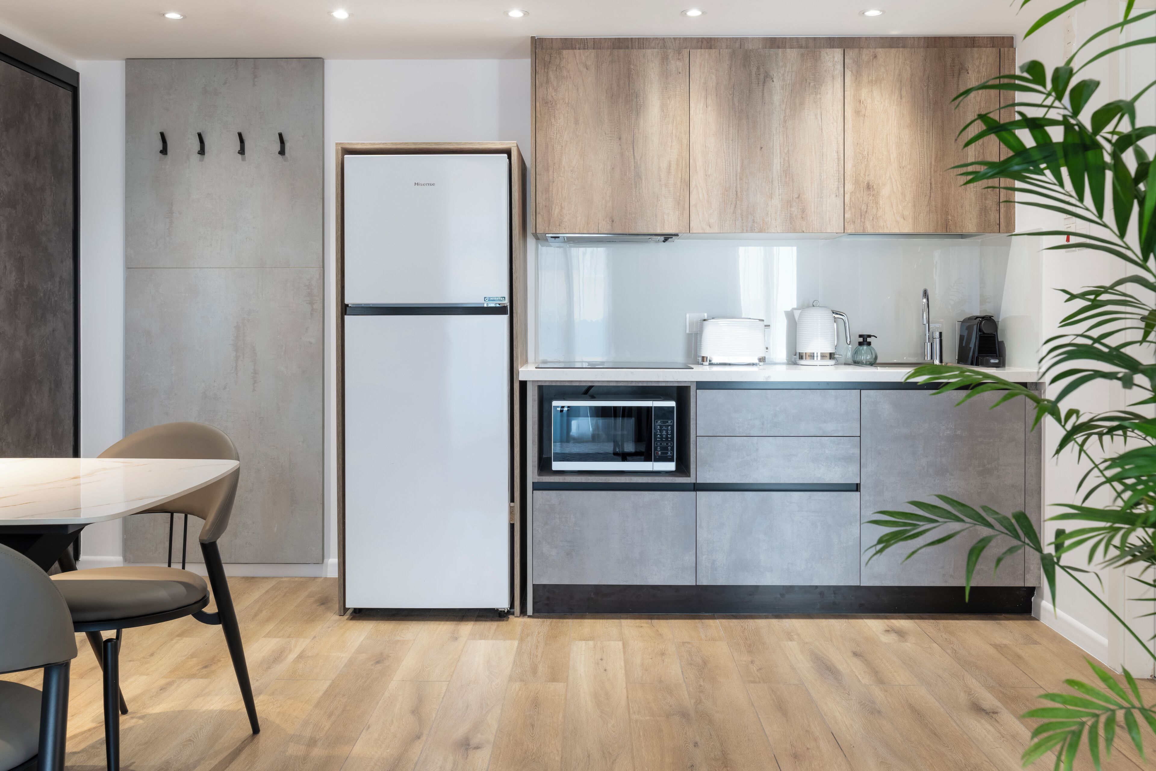 A modern kitchen with a built-in microwave, a refrigerator, and wooden cabinets.