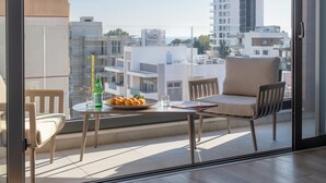 Ein Balkon mit Tisch, Stühlen, einer Obstschale und einer Wasserflasche.