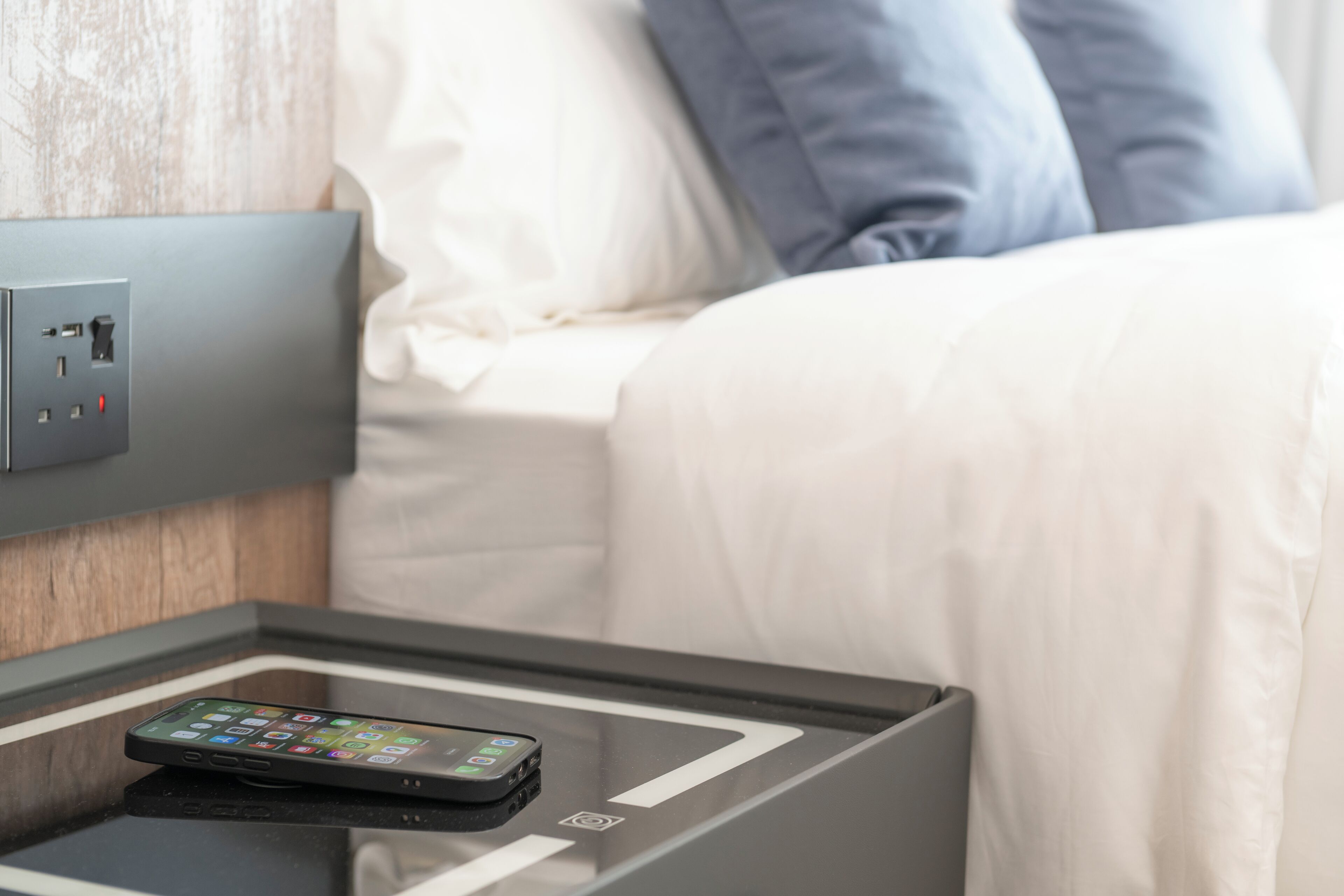 Une chambre d’hôtel équipée d’une table de chevet, d’une prise électrique et d’une station de recharge.