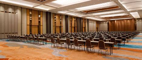 A conference room with rows of tables and chairs, a patterned carpet, and a modern ceiling design.