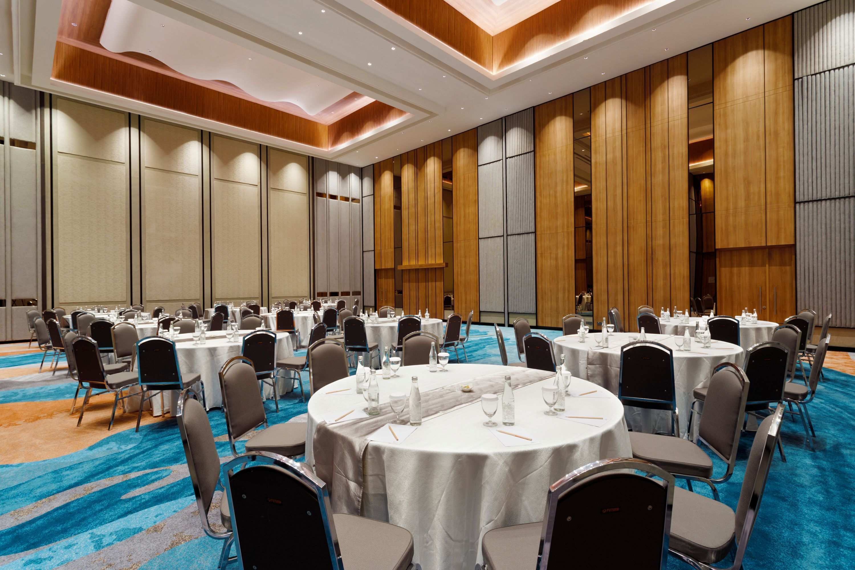 A conference room with round tables, chairs, and a blue carpet.