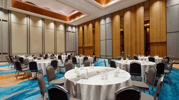 A conference room with round tables, chairs, and a blue carpet.