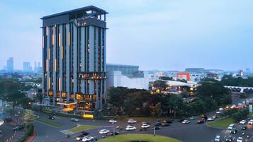 A multi-story building with a prominent vertical design, surrounded by a landscaped area with a circular design feature.