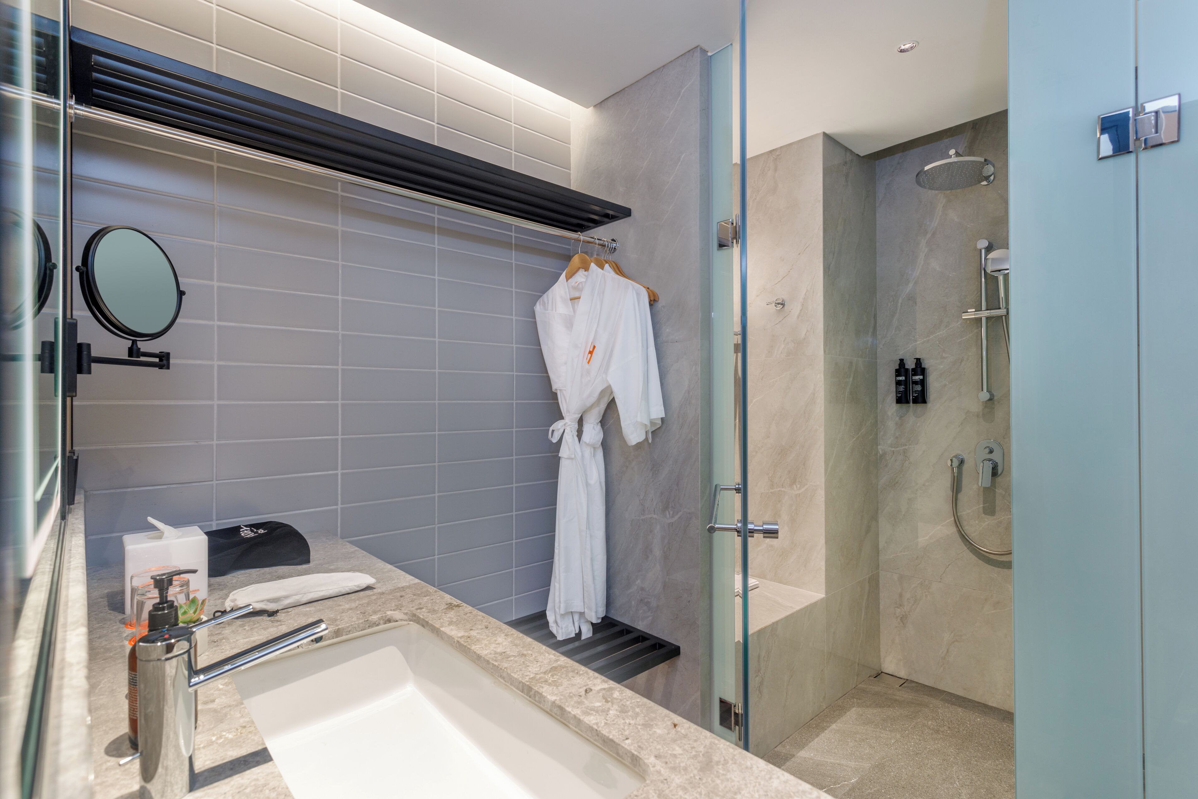 A modern bathroom with a bathtub, a glass-enclosed shower, and a towel rack with a white robe.