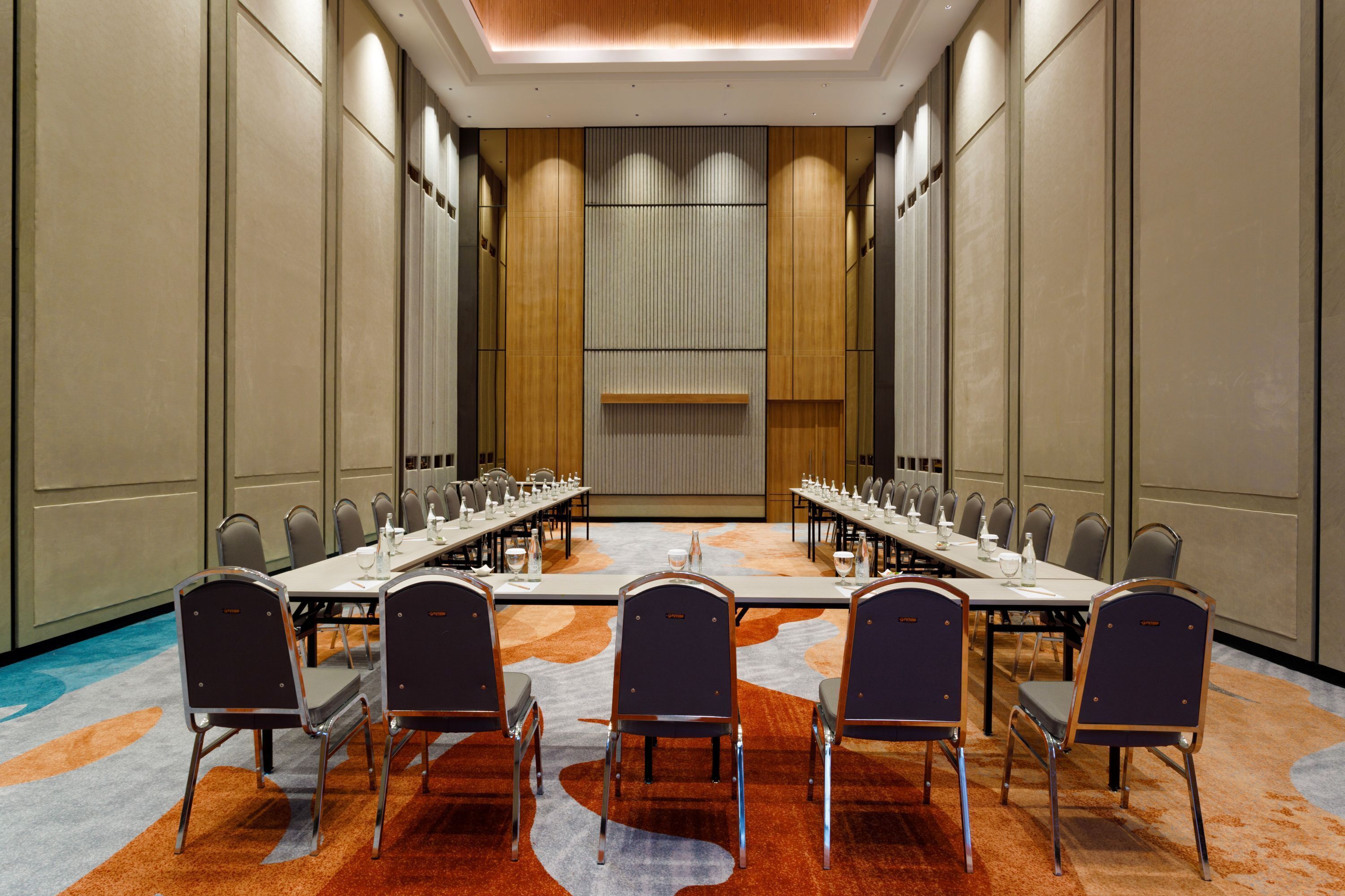 A conference room with a long table, multiple chairs, and a carpeted floor.