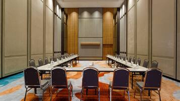 A conference room with a long table, multiple chairs, and a carpeted floor.