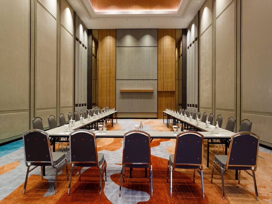 A conference room with a long table, multiple chairs, and a carpeted floor.